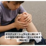 膝の痛みを抱える小学生の男の子がアスファルトの上で膝を押さえている様子