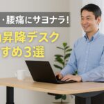 腰痛予防のために電動昇降デスクを使って立ち作業をする中年の日本人男性が、ノートパソコンに向かって微笑みながら仕事をしている様子。